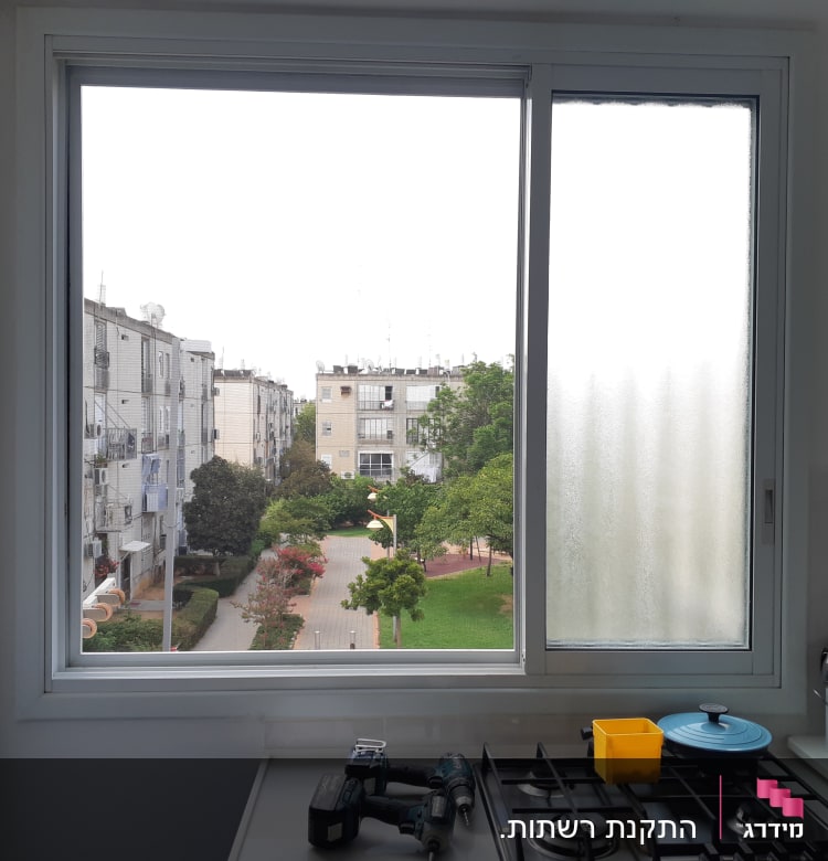 חלון אלומיניום עם נוף חיצוני וכלי עבודה